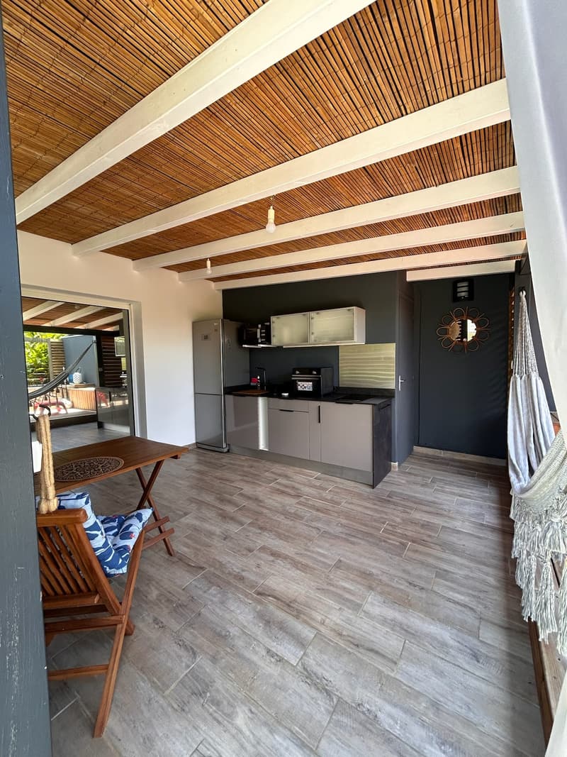 La terrasse couverte vue depuis l'intérieur, cuisine d'extérieur au fond