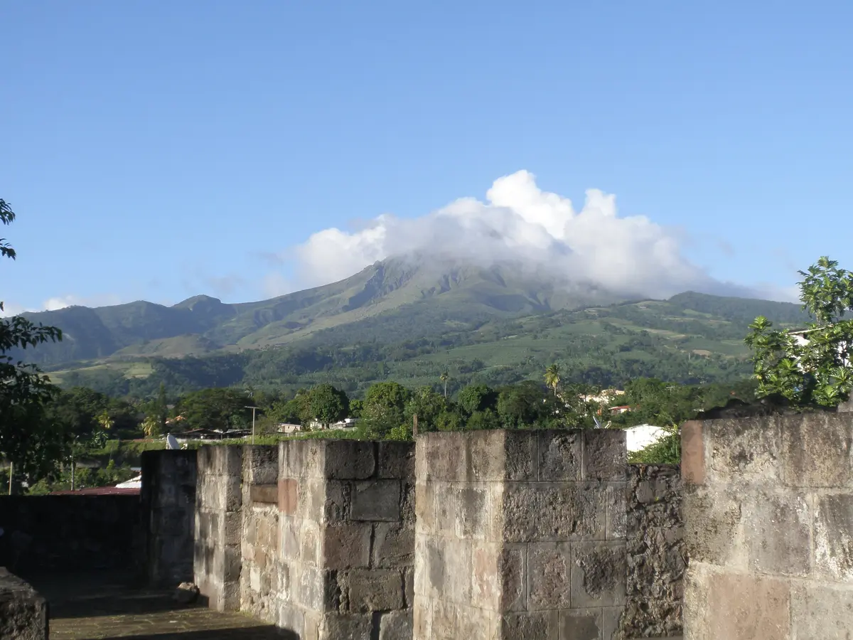 The remains of the Saint-Pierre theater, Mount Pelée in the clouds