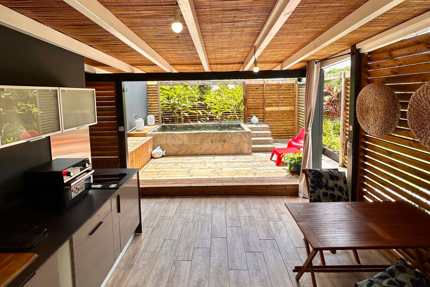 The terrace under its bamboo ceiling, the outdoor kitchen and the pool at the back
