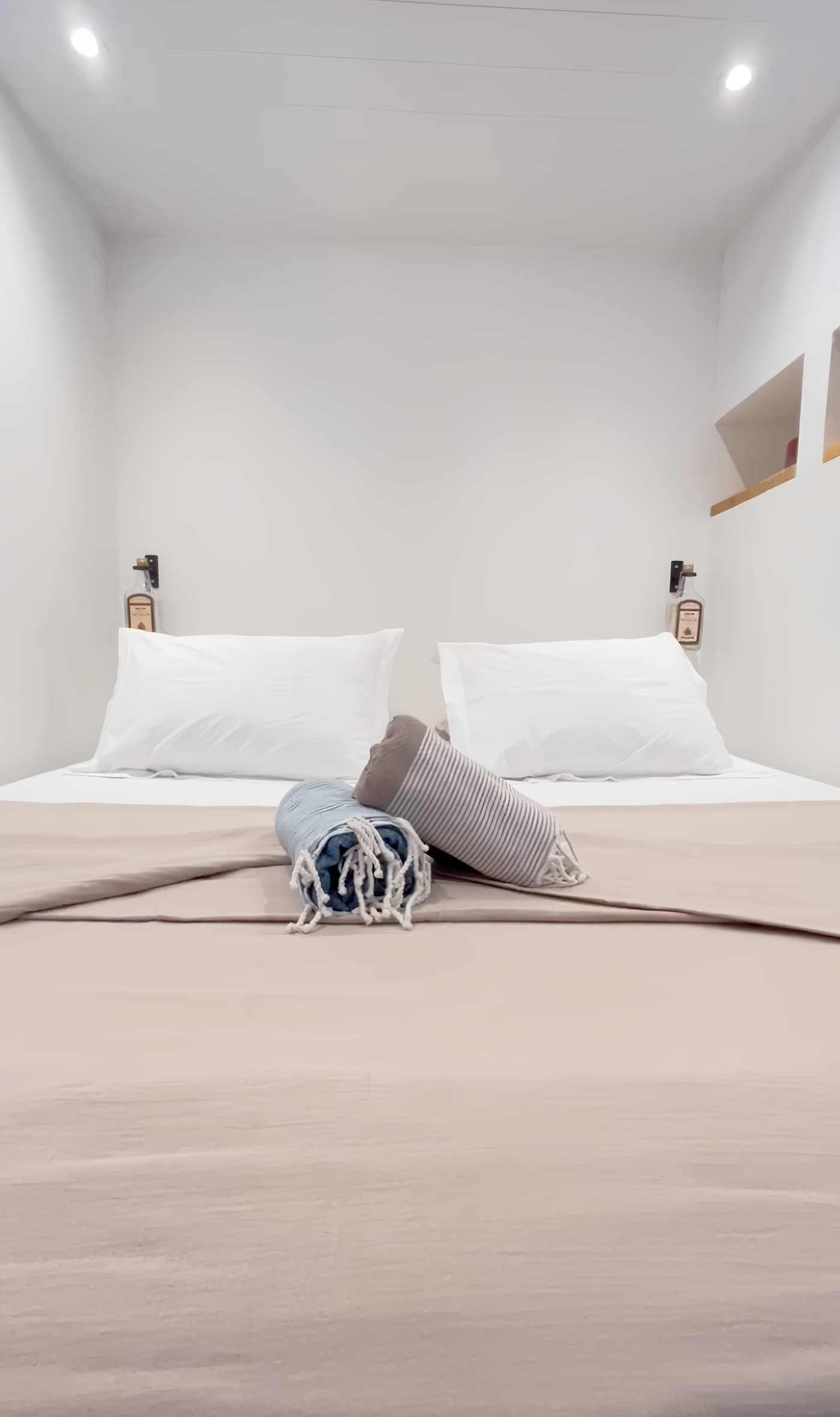 The bedroom: the king-size bed with white sheets, two pillows and rolled foutas