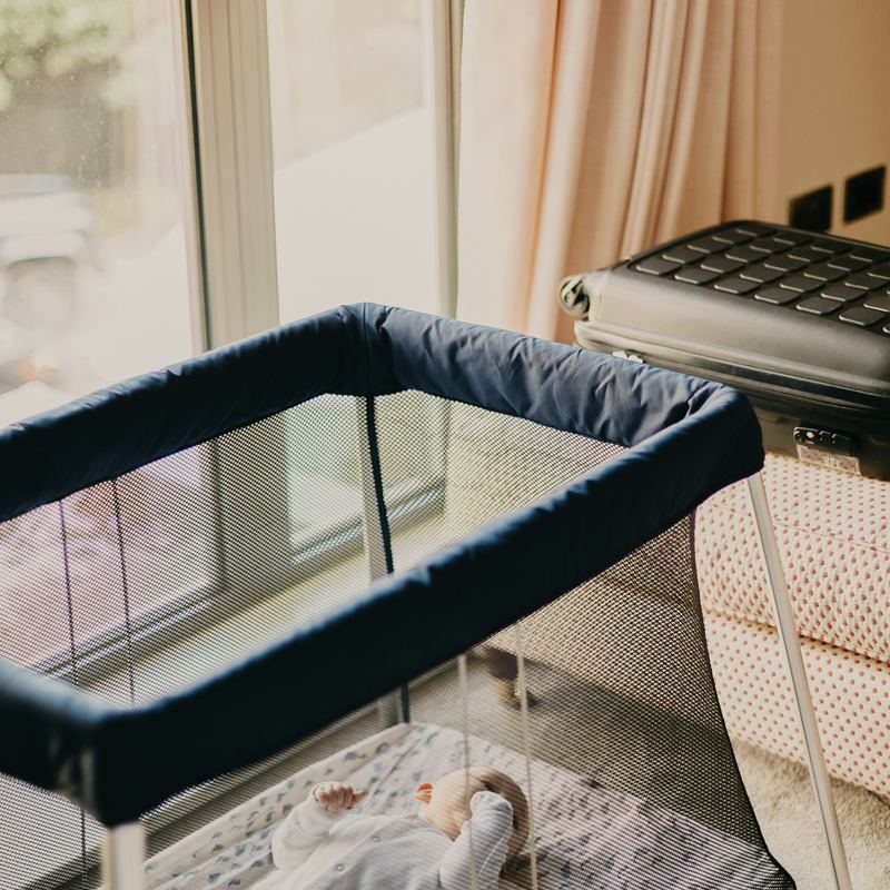 A travel cot with mesh sides, in a bedroom